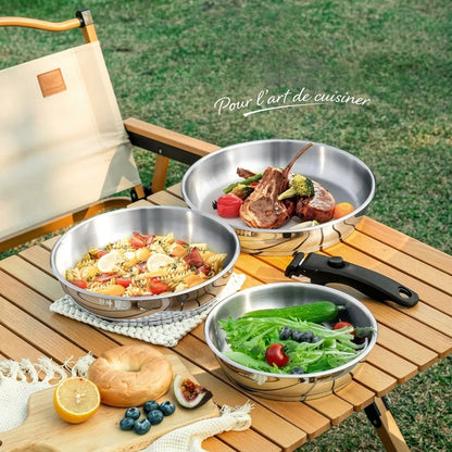 Poêles inox à manche amovible utilisées en extérieur sur une table de camping