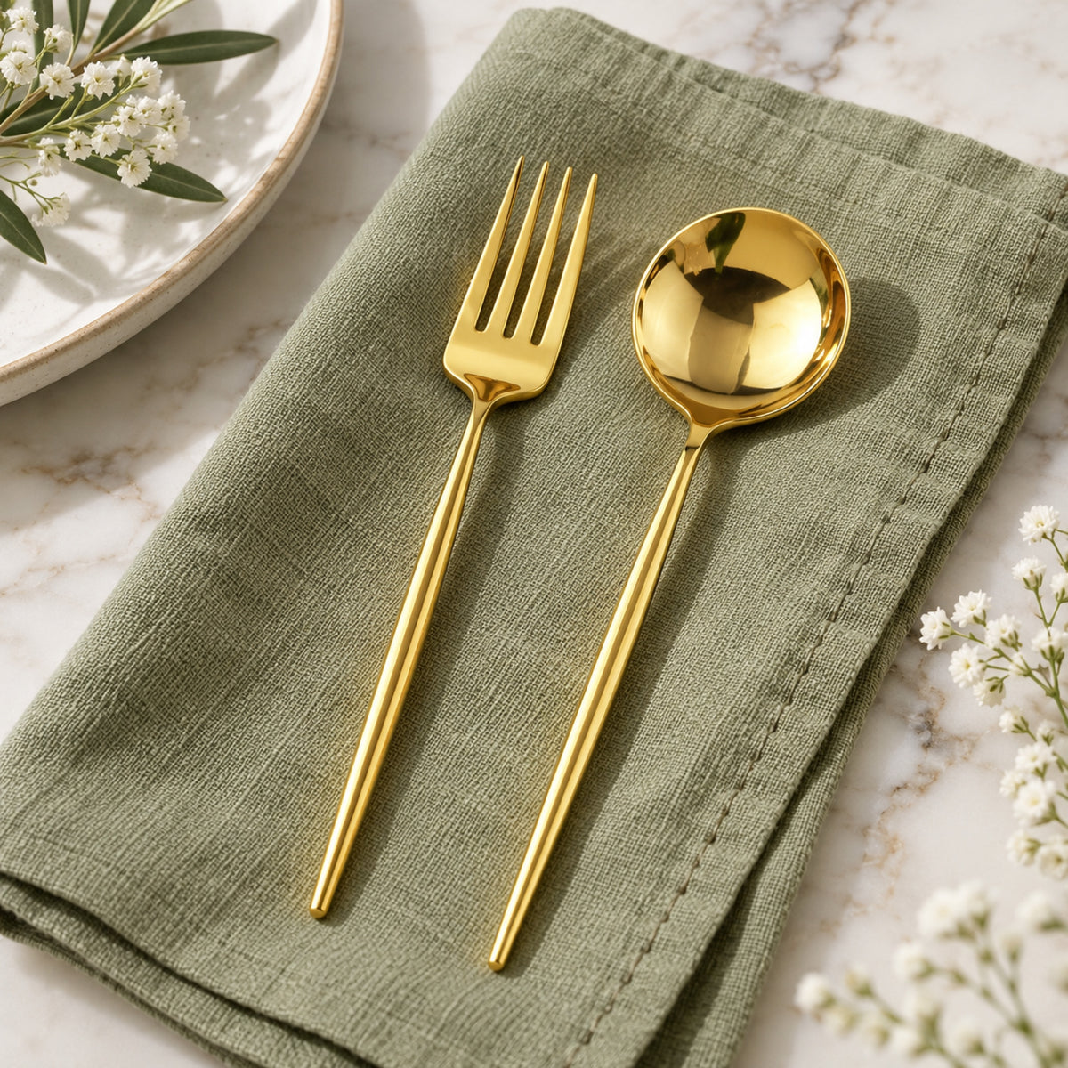 Fourchette et cuillère dorées poli miroir sur une serviette en lin vert sauge